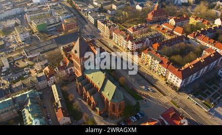 Un drone capture le centre-ville de Koszalin baigné de lumière dorée, avec la cathédrale, Victory Street et l'hôtel de ville. Banque D'Images