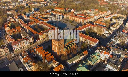 Un drone capture le centre-ville de Koszalin baigné de lumière dorée, avec la cathédrale, Victory Street et l'hôtel de ville. Banque D'Images