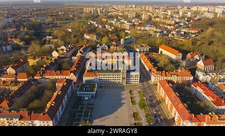 Un drone capture le centre-ville de Koszalin baigné de lumière dorée, avec la cathédrale, Victory Street et l'hôtel de ville. Banque D'Images