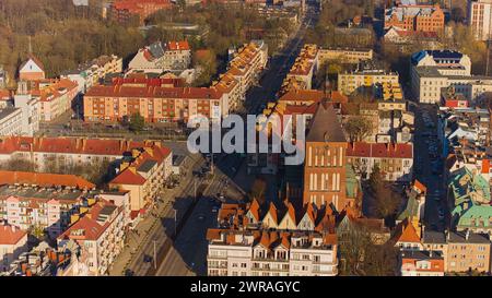 Un drone capture le centre-ville de Koszalin baigné de lumière dorée, avec la cathédrale, Victory Street et l'hôtel de ville. Banque D'Images