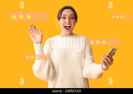 Femme excitée donnant une note à la nouvelle application mobile sur fond jaune Banque D'Images
