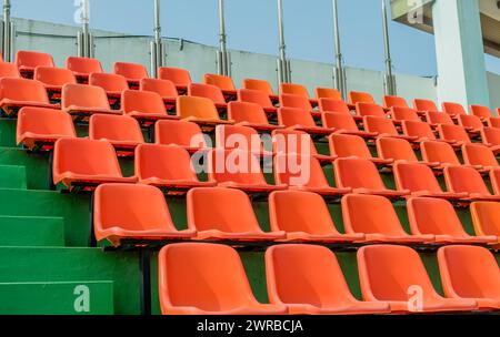 Rangées de sièges orange vides montant les marches vertes dans un stade, en Corée du Sud Banque D'Images