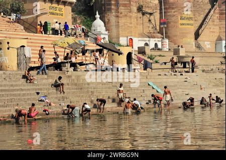 Les gens se baignent et socialisent dans les ghats animés d'une rivière indienne, Varanasi, Uttar Pradesh, Inde Banque D'Images