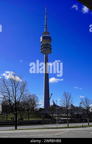 Une grande tour de télévision s'élève dans le ciel bleu avec des arbres au premier plan, BMW WELT, Munich, Allemagne Banque D'Images