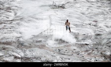 Travailleur appliquer du calcaire agricole pour néautraliser l'acidité du sol, ajustant le ph pour la ferme prête, poudre blanche étalée sur la surface de la terre au Vietnam Banque D'Images