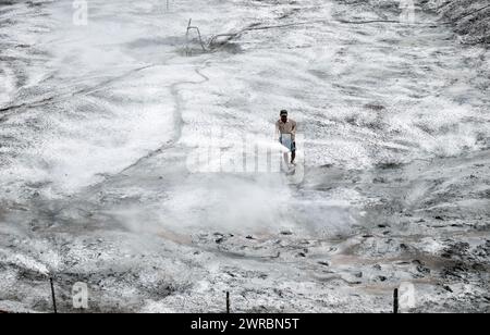 Travailleur appliquer du calcaire agricole pour néautraliser l'acidité du sol, ajustant le ph pour la ferme prête, poudre blanche étalée sur la surface de la terre au Vietnam Banque D'Images