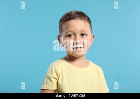 Garçon mignon avec moustache au lait sur fond bleu clair Banque D'Images