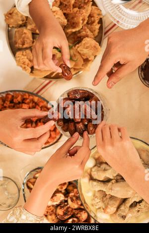 Mains prendre des dattes fruits ou Kurma, concept Buka Bersama, partage de nourriture pendant le mois de jeûne du Ramadan, briser le jeûne ensemble Banque D'Images