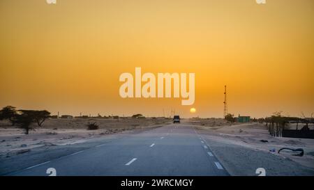 Conduite à travers un village dans le désert en Mauritanie au coucher du soleil Banque D'Images