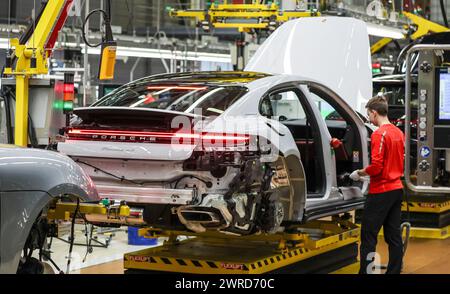 Leipzig, Allemagne. 11 mars 2024. Un employé assemble une Porsche Panamera à l'usine de Leipzig. Le constructeur de véhicules sportifs et tout-terrain Porsche publiera ses chiffres d'affaires de l'année écoulée mardi 12 mars à l'usine Porsche de Leipzig. Crédit : Jan Woitas/dpa/Alamy Live News Banque D'Images