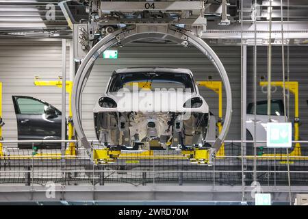 Leipzig, Allemagne. 11 mars 2024. Une Porsche Macan flotte sous le plafond dans le hall de montage de l'usine de Leipzig. Le constructeur de véhicules de sport et tout-terrain Porsche publie mardi (12 mars) ses chiffres d'affaires de l'année écoulée à l'usine Porsche de Leipzig. Crédit : Jan Woitas/dpa/Alamy Live News Banque D'Images