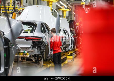 Leipzig, Allemagne. 11 mars 2024. Un employé assemble une Porsche Macan à l'usine de Leipzig. Le constructeur de véhicules sportifs et tout-terrain Porsche publiera ses chiffres d'affaires de l'année écoulée mardi 12 mars à l'usine Porsche de Leipzig. Crédit : Jan Woitas/dpa/Alamy Live News Banque D'Images