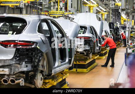 Leipzig, Allemagne. 11 mars 2024. Un employé assemble une Porsche Macan à l'usine de Leipzig. Le constructeur de véhicules sportifs et tout-terrain Porsche publiera ses chiffres d'affaires de l'année écoulée mardi 12 mars à l'usine Porsche de Leipzig. Crédit : Jan Woitas/dpa/Alamy Live News Banque D'Images