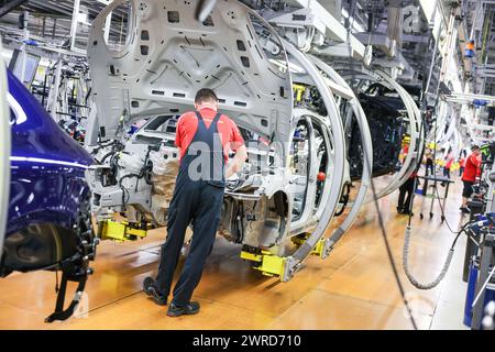 Leipzig, Allemagne. 11 mars 2024. Un employé assemble une Porsche Macan à l'usine de Leipzig. Le constructeur de véhicules sportifs et tout-terrain Porsche publiera ses chiffres d'affaires de l'année écoulée mardi 12 mars à l'usine Porsche de Leipzig. Crédit : Jan Woitas/dpa/Alamy Live News Banque D'Images