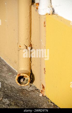 détail d'un vieux tuyau de fer sur un mur peint en jaune Banque D'Images