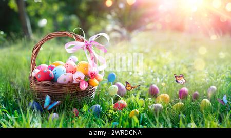 Oeufs de Pâques dans un panier sur herbe avec papillons et lumières Bokeh abstraites Banque D'Images