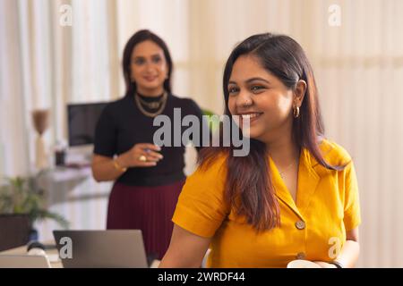 Deux femmes d'affaires discutant projet sur ordinateur portable au poste de travail de bureau Banque D'Images