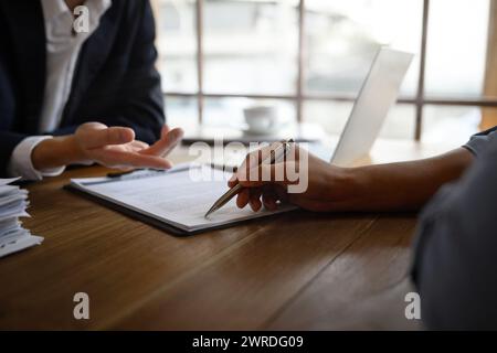 Gros plan avocat ou agent d'assurance pointant le contrat montrant au client masculin où signer Banque D'Images