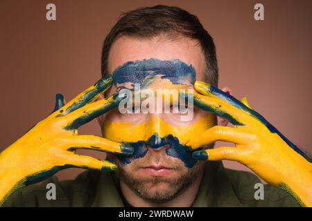 Homme exprimant son respect à l'Ukraine avec des couleurs nationales sur le visage Banque D'Images