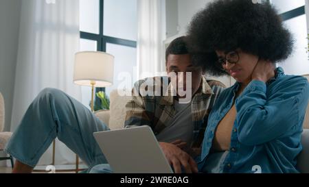 Triste stressé femme africaine problème d'ordinateur portable virus spam ordinateur cassé à la maison homme essayant d'aider couple désaccord en ligne en utilisant Internet Banque D'Images