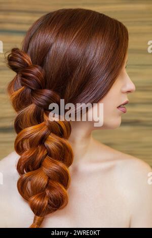 Belle fille aux longs cheveux roux, tressée avec une tresse française, dans un salon de beauté. Soins capillaires professionnels et création de coiffures. Banque D'Images