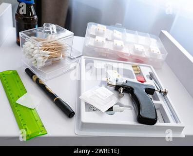 La table avec les instruments stériles du cosmétologue qui se prépare à effectuer le perçage des oreilles d'une jeune femme. Photo de haute qualité Banque D'Images