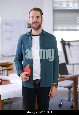 Portrait, sourire et cahier avec architecte homme dans le bureau avec des documents pour la construction, la conception ou la planification. Architecture, construction et création Banque D'Images