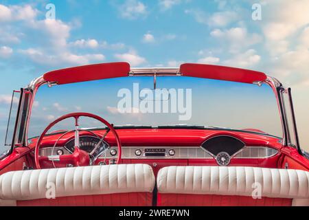 Vue du conducteur d'une voiture cabriolet américaine vintage classique rouge ouverte devant un ciel bleu ensoleillé Banque D'Images