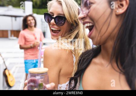 Rire jeune femme caucasienne avec des cheveux blonds et des lunettes de soleil est avec une femme biraciale Banque D'Images