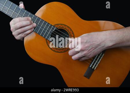 Guy joue de la guitare acoustique. Isolé sur noir Banque D'Images