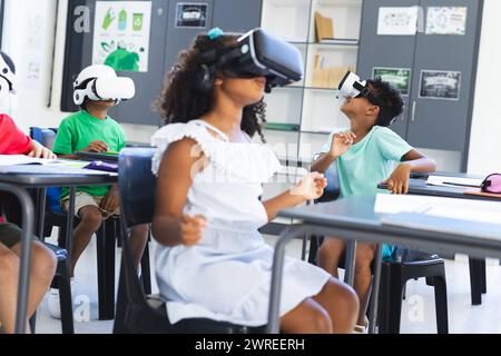 Divers enfants utilisent des casques de réalité virtuelle dans une salle de classe à l'école Banque D'Images