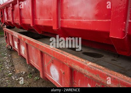 Grandes cuves de recyclage rouges usagées empilées avec des marques d'utilisation et de la rouille. Banque D'Images