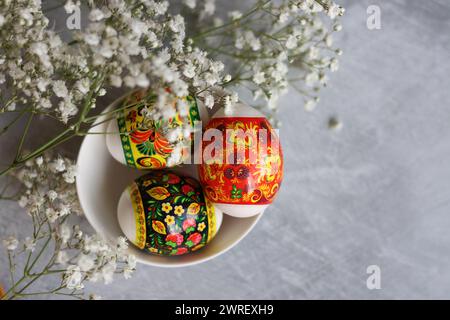 Oeufs de Pâques sur une table. Nature morte avec des fleurs blanches et des œufs. Photo vue de dessus d'oeufs colorés sur une table. Concept de vacances de Pâques. Banque D'Images