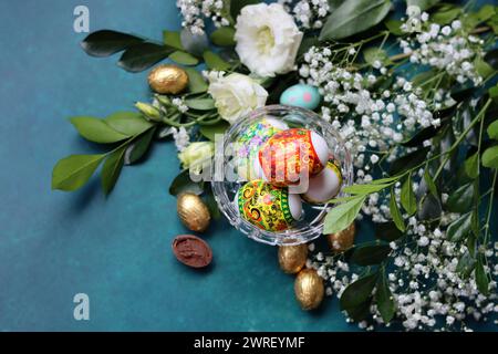 Oeufs de Pâques sur une table. Nature morte avec des fleurs blanches et des œufs. Photo vue de dessus d'oeufs colorés sur une table. Concept de vacances de Pâques. Banque D'Images