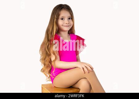 Gymnaste blonde assis sur une chaise en bois dans un studio avec un fond blanc, regardant la caméra avec le sourire. Photo de haute qualité Banque D'Images