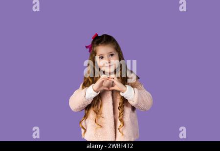 L'image d'une petite fille très élégante habillée comme elle montre un cœur fait de ses mains désignées à sa mère et montrant qu'elle aime son ver Banque D'Images