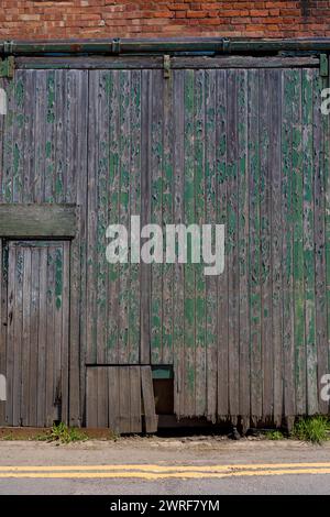Vieux murs de briques et portes en bois peintes en vert lourd et fanées, Knighton, Powys. Banque D'Images