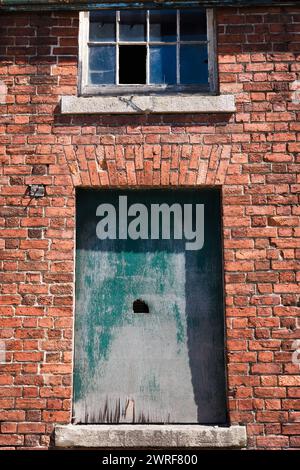 Vieux murs de briques et portes en bois peintes en vert lourd et fanées, Knighton, Powys. Banque D'Images