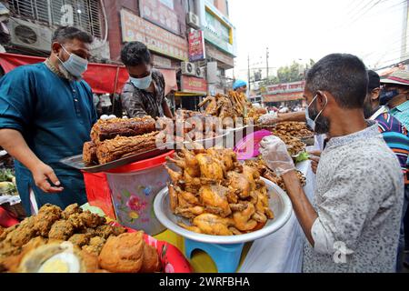 Les musulmans bangladais achètent de la nourriture pour rompre leur jeûne pendant le premier jour du mois de jeûne du Ramadan sur un marché alimentaire traditionnel au bazar de Chalk, à Dhaka, au Bangladesh, le 12 mars 2024. Le mois sacré du Ramadan pour les musulmans est le neuvième mois du calendrier islamique, et on croit que la révélation du premier verset du Coran a eu lieu au cours de ses 10 dernières nuits. C’est aussi un moment de socialisation, principalement le soir après avoir rompu le jeûne, et un déplacement de toutes les activités vers la fin de la journée dans la plupart des pays. Photo Habibur Rahman/ABACAPRESS.COM Banque D'Images