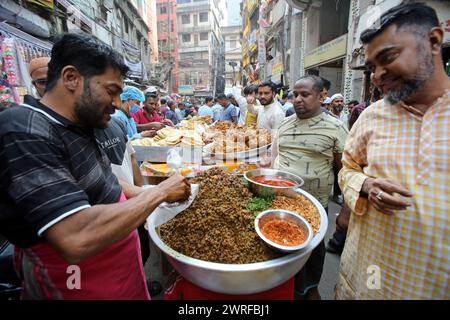 Les musulmans bangladais achètent de la nourriture pour rompre leur jeûne pendant le premier jour du mois de jeûne du Ramadan sur un marché alimentaire traditionnel au bazar de Chalk, à Dhaka, au Bangladesh, le 12 mars 2024. Le mois sacré du Ramadan pour les musulmans est le neuvième mois du calendrier islamique, et on croit que la révélation du premier verset du Coran a eu lieu au cours de ses 10 dernières nuits. C’est aussi un moment de socialisation, principalement le soir après avoir rompu le jeûne, et un déplacement de toutes les activités vers la fin de la journée dans la plupart des pays. Photo Habibur Rahman/ABACAPRESS.COM Banque D'Images