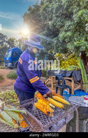 vendeur de rue africain griller du maïs doux sur le bord de la route dans une cabane Banque D'Images