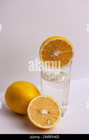 Sur un fond blanc, un verre d'eau avec un fruit de citron jaune à côté est montré, un mode de vie sain est montré. Photo de haute qualité Banque D'Images