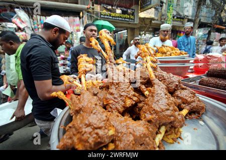 12 mars 2024, Dhaka, Wari, Bangladesh : les musulmans bangladais achètent de la nourriture pour rompre leur jeûne pendant le premier jour du mois de jeûne du Ramadan sur un marché alimentaire traditionnel au bazar de Chalk, à Dhaka, Bangladesh, le 12 mars 2024. Le mois sacré du Ramadan pour les musulmans est le neuvième mois du calendrier islamique, et on croit que la révélation du premier verset du Coran a eu lieu au cours de ses 10 dernières nuits. C’est aussi un moment de socialisation, principalement le soir après avoir rompu le jeûne, et un déplacement de toutes les activités vers la fin de la journée dans la plupart des pays. (Crédit image : © Habibur Rahman/ZUMA Pre Banque D'Images