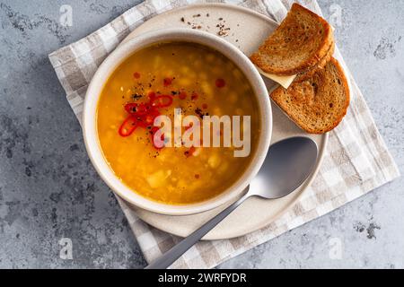 Bol de soupe de haricots de lentilles avec sandwich au fromage de pain de seigle sur fond gris, nourriture de confort saine, vue en angle élevé Banque D'Images