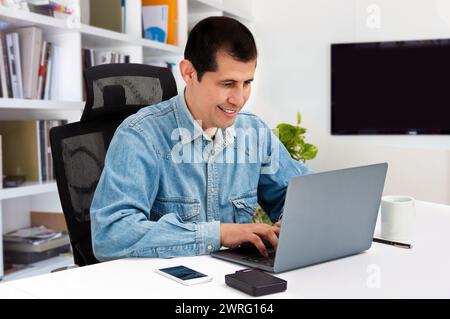 Photo d'un beau jeune homme d'affaires assis derrière son ordinateur portable dans son bureau Banque D'Images