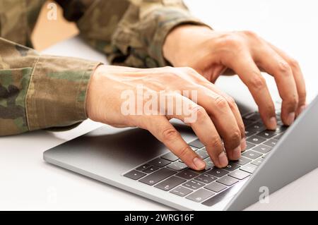 Gros plan d'un militaire méconnaissable tapant sur un clavier d'ordinateur portable Banque D'Images