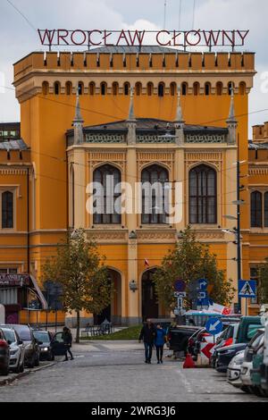 Wroclaw, Pologne - 12 novembre 2023 : façade magnifiquement rénovée du bâtiment principal de la gare ferroviaire au bout de la rue avec de grandes lumières la nuit n Banque D'Images