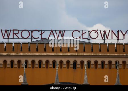 Wroclaw, Pologne - 12 novembre 2023 : façade magnifiquement rénovée du bâtiment principal de la gare ferroviaire au bout de la rue avec de grandes lumières la nuit n Banque D'Images