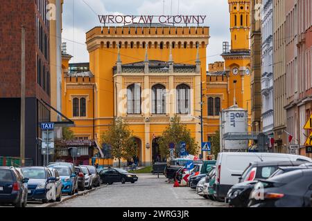 Wroclaw, Pologne - 12 novembre 2023 : façade magnifiquement rénovée du bâtiment principal de la gare ferroviaire au bout de la rue avec de grandes lumières la nuit n Banque D'Images