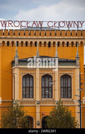 Wroclaw, Pologne - 12 novembre 2023 : façade magnifiquement rénovée du bâtiment principal de la gare ferroviaire au bout de la rue avec de grandes lumières la nuit n Banque D'Images